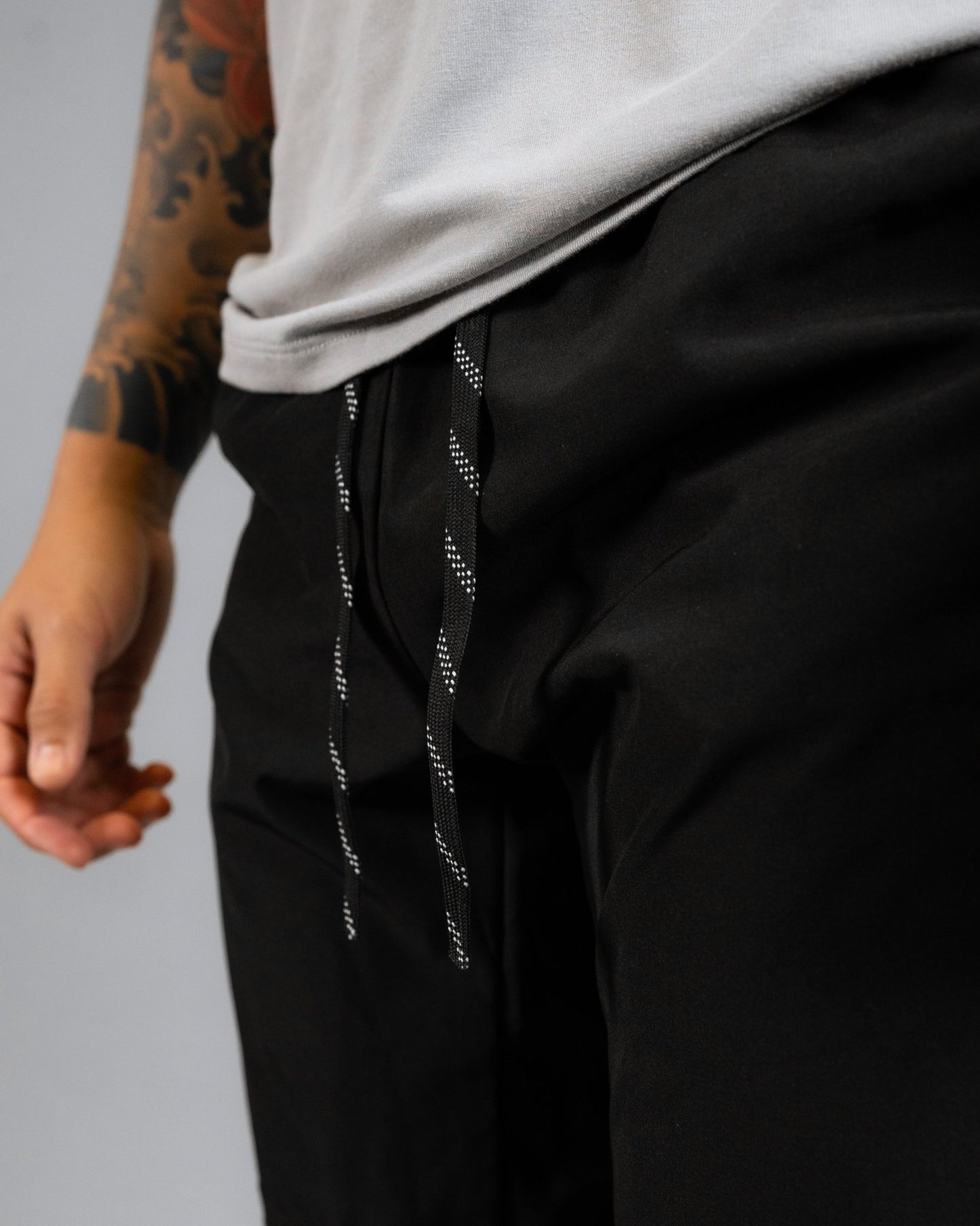 close up of model wearing the ALL IN ALL black supernatural short showcasing the black and white striped interior drawcord pulled out
