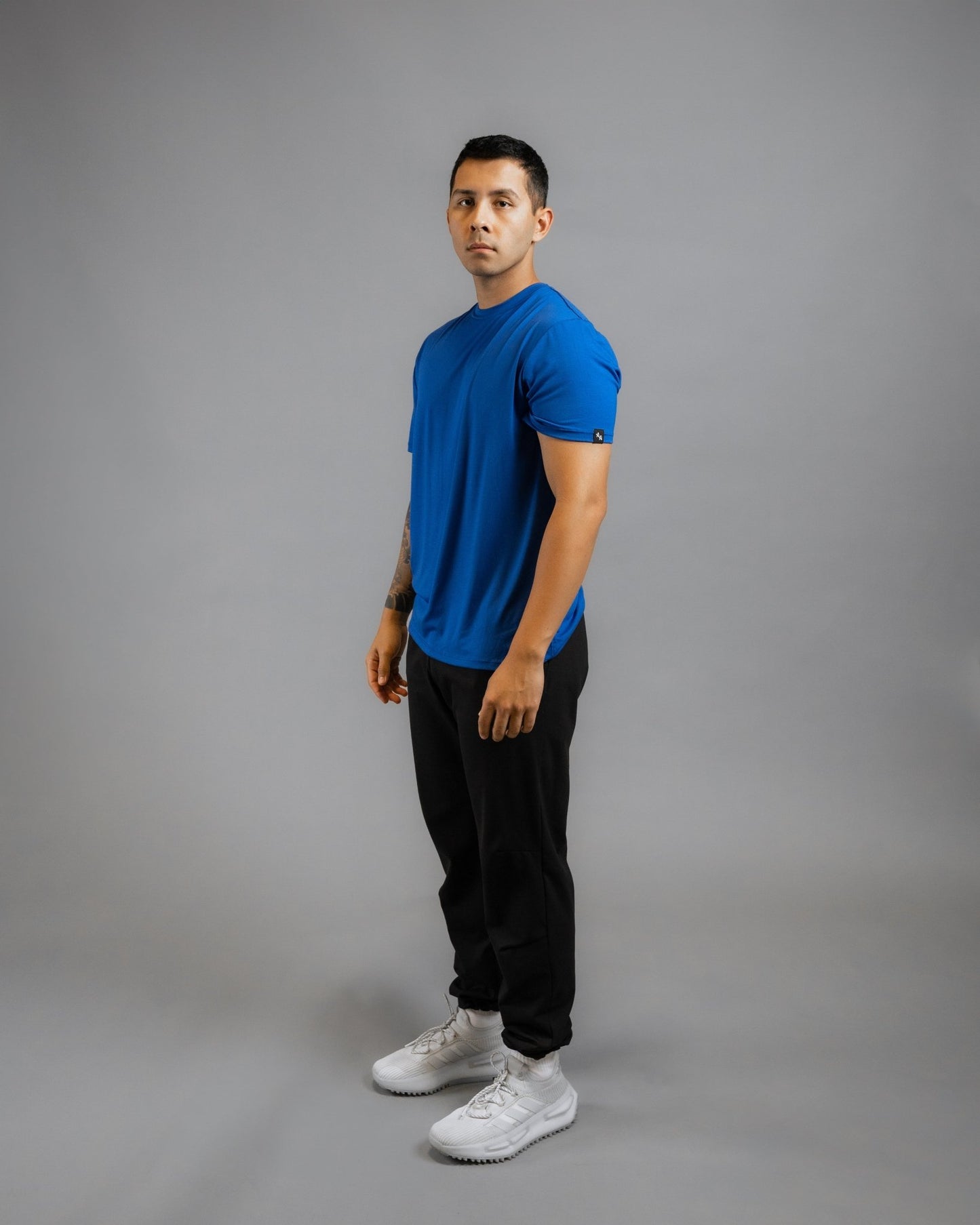 model standing 3/4 facing forward wearing ALL IN ALL blue supernatural tee with black supernatural II jogger