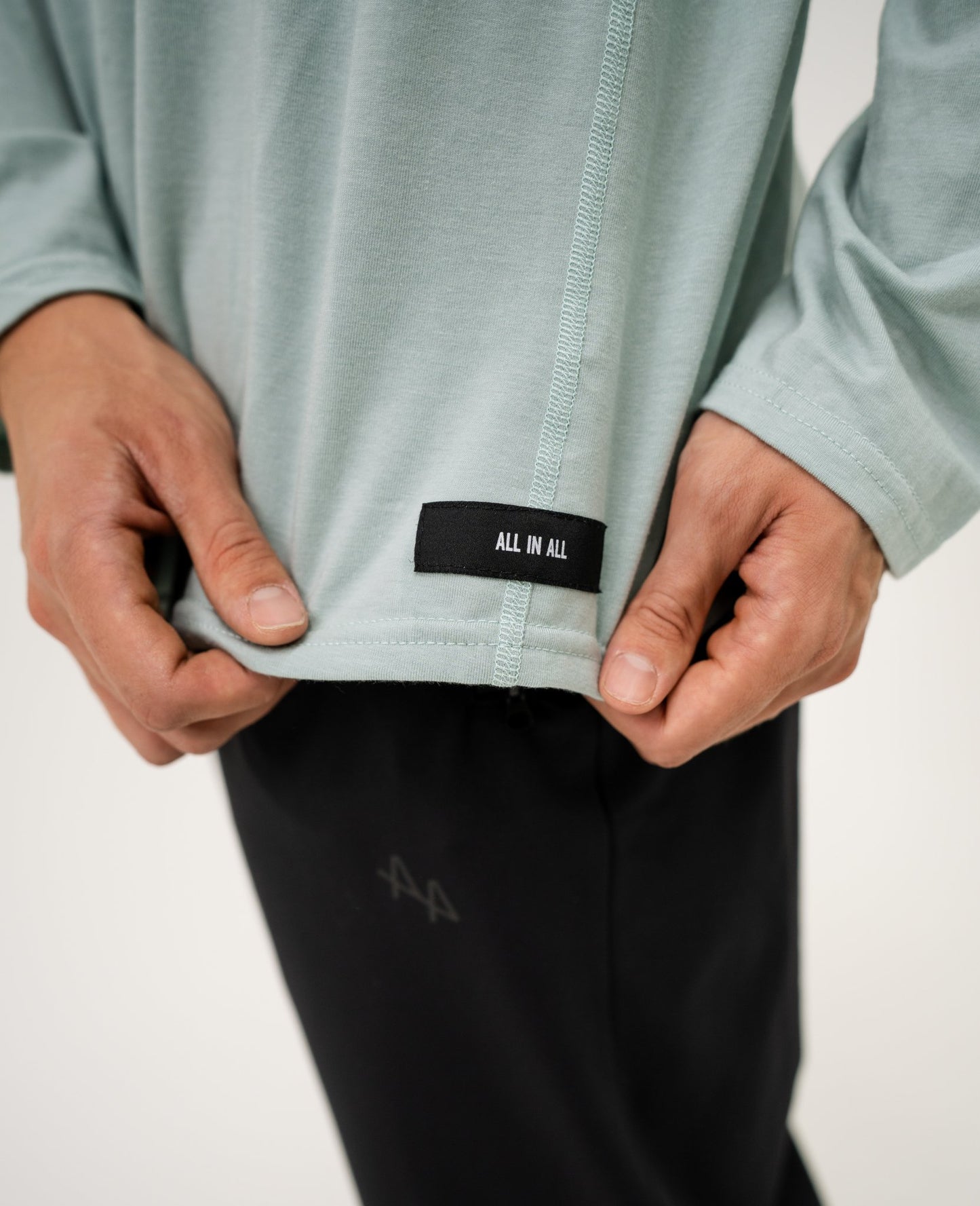 Person wearing an ALL IN ALL mojito long-sleeve hoodie shirt with a black label on a white background