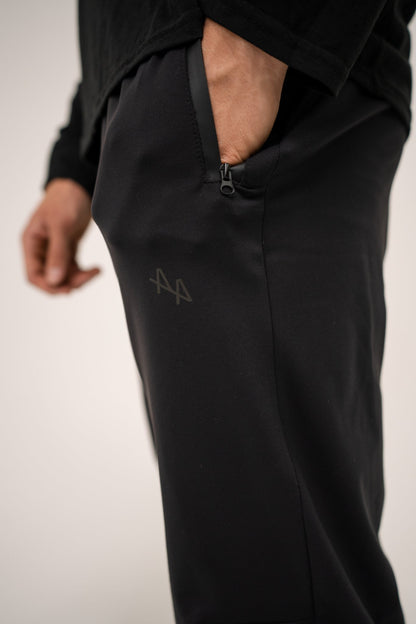 Close up of Supernatural II joggers with model's hand in zippered pocket highlighting black matte ALL IN ALL logo