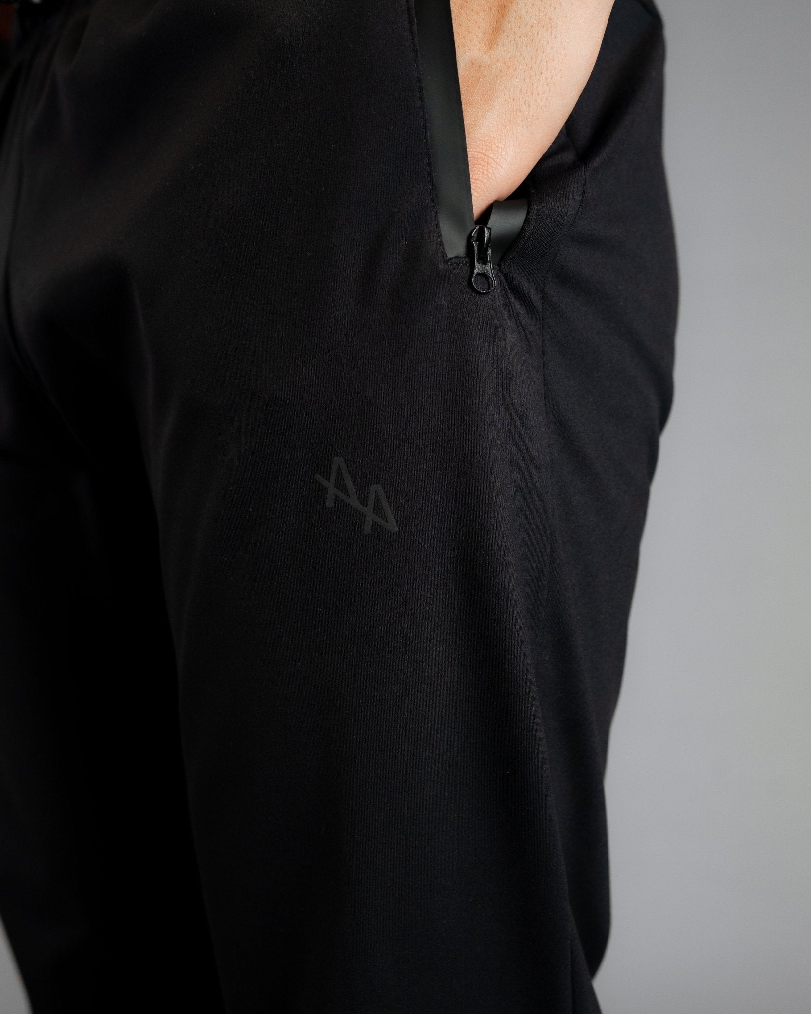 Close up of model with hand in left pocket on the SUPERNATURAL II JOGGER - ALL IN ALL. Showing the black matte waterproof zipper detail.