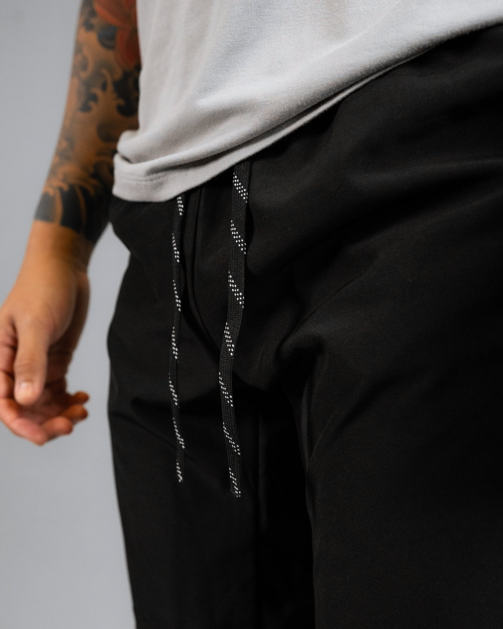 close up of model wearing the ALL IN ALL black supernatural short showcasing the black and white striped  interior drawcord pulled out