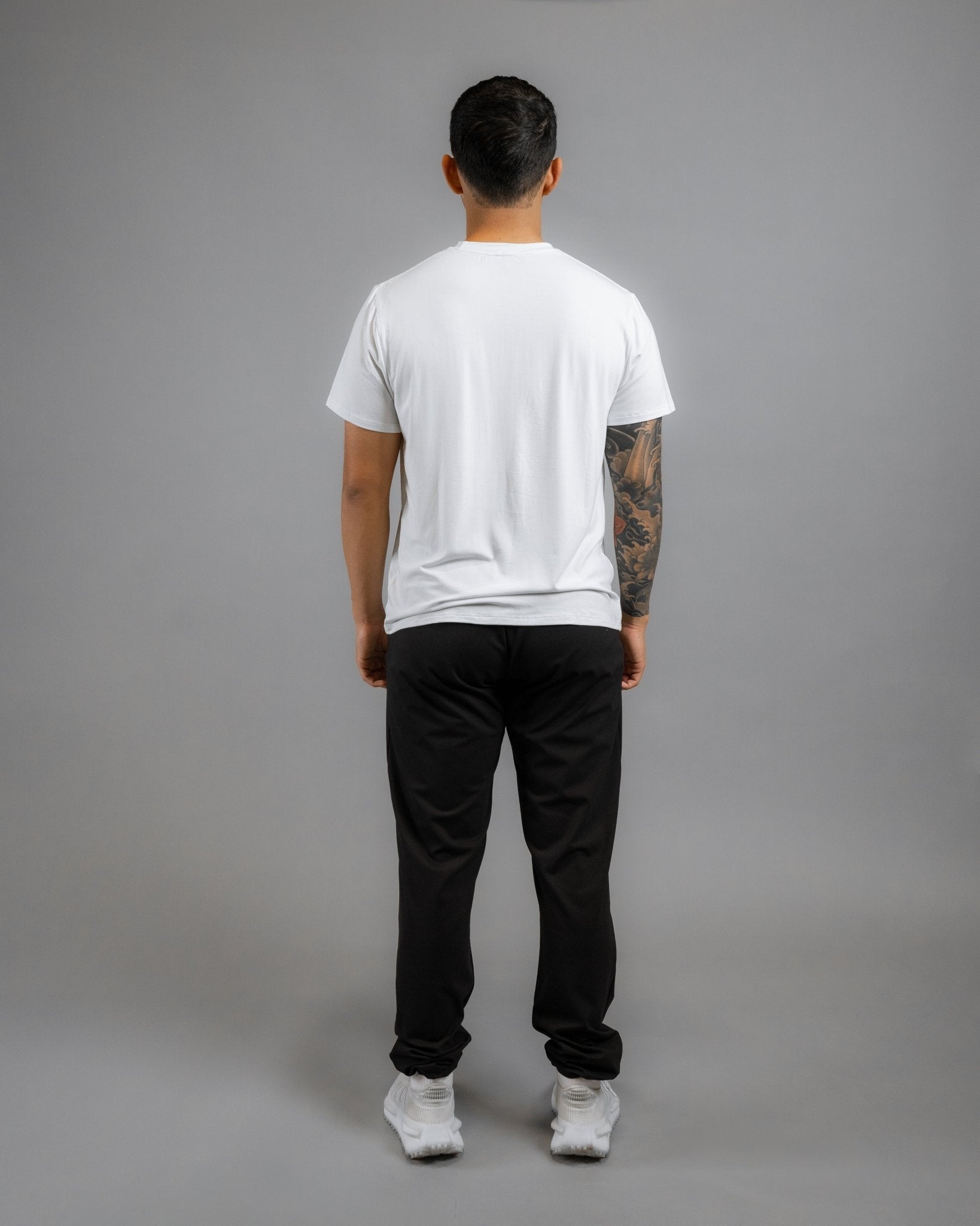 backside of model wearing ALL IN ALL off-white supernatural tee with black supernatural II jogger