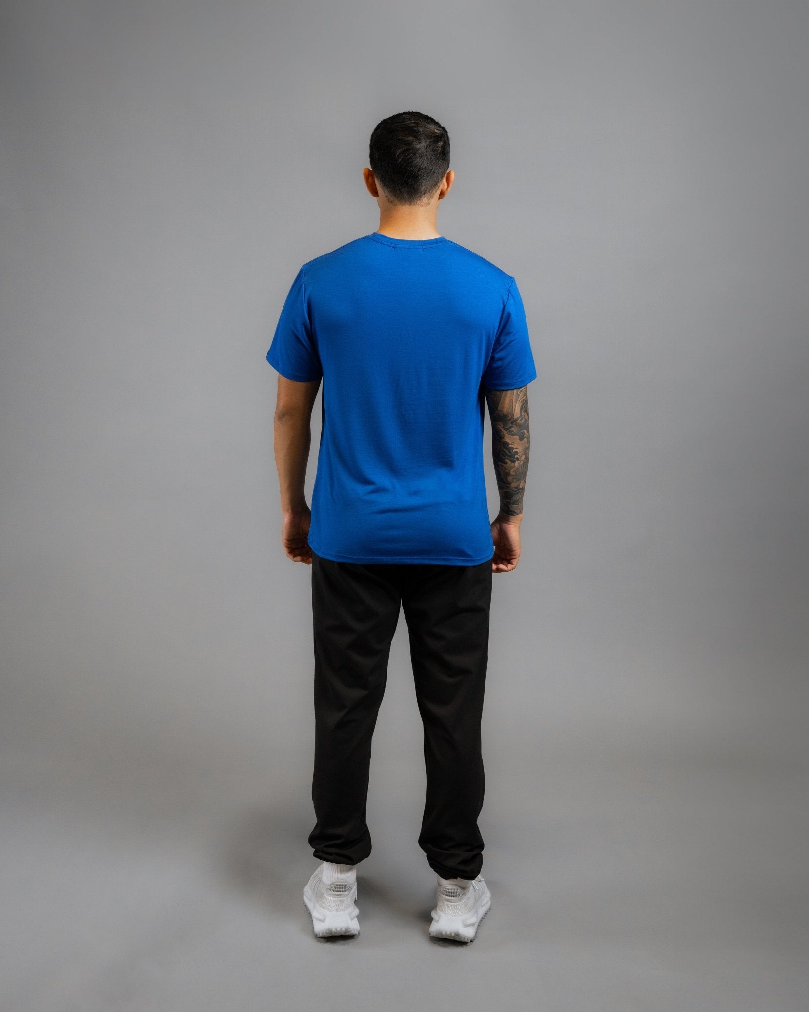 backside of model wearing ALL IN ALL blue supernatural tee with black supernatural II jogger