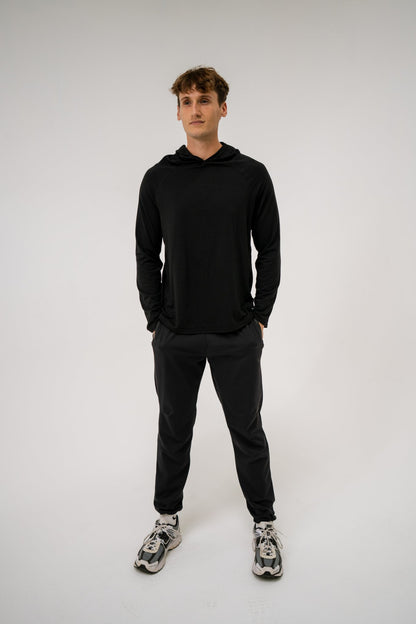Male model wearing an ALL IN ALL black hoodie and ALL IN ALL black joggers against a white background