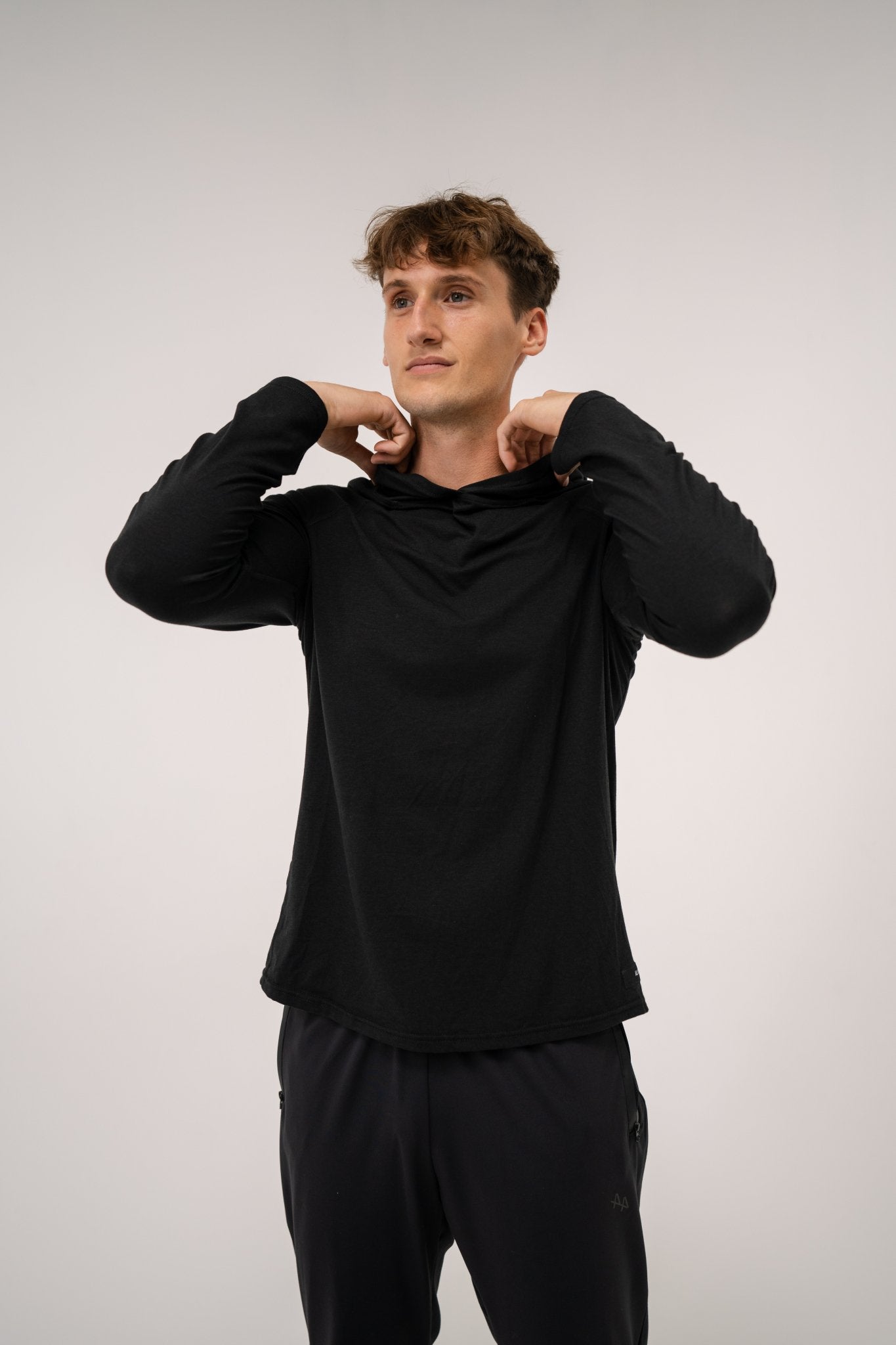 Male model wearing an ALL IN ALL black hoodie and ALL IN ALL black joggers against a plain background