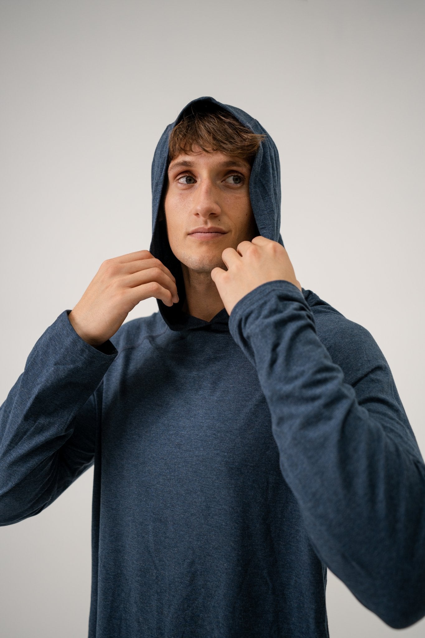 Male model wearing an ALL IN ALL heather blue hoodie shirt against a plain background
