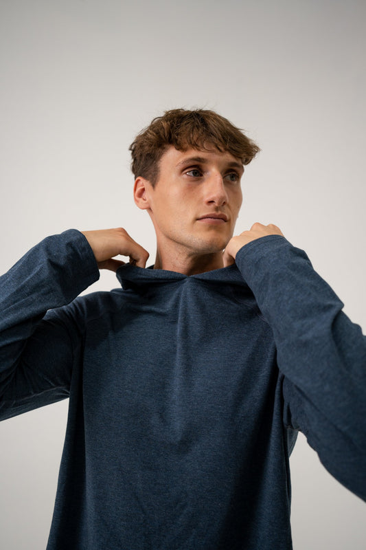 Male model wearing an ALL IN ALL heather blue long-sleeve hoodie shirt against a plain background