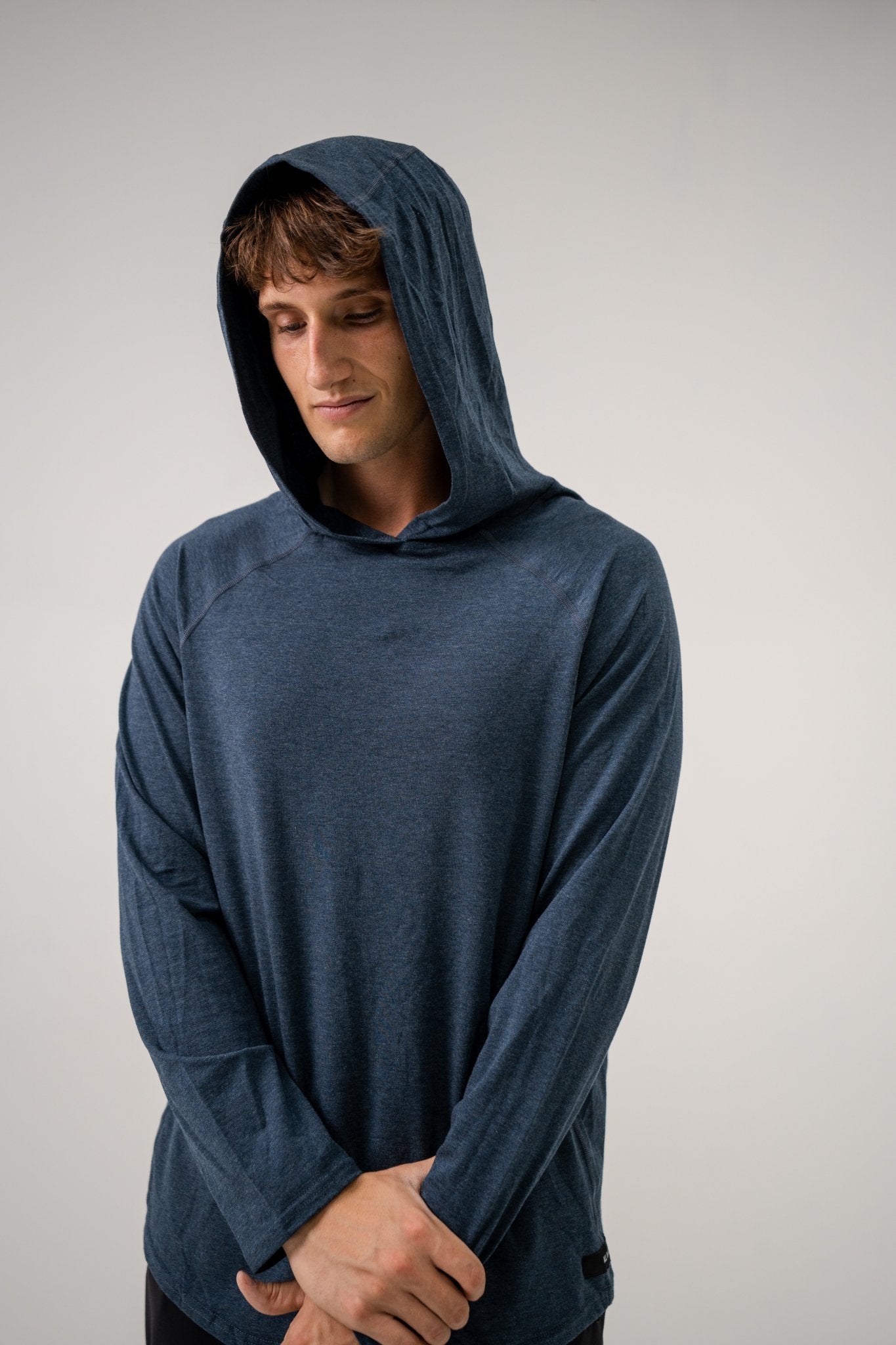 Male model wearing an ALL IN ALL heather blue hoodie against a plain background