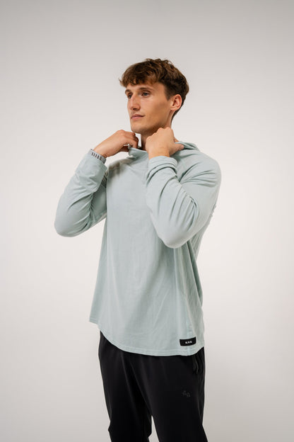 Male model wearing an ALL IN ALL mojito long-sleeve hoodie shirt and ALL IN ALL black joggers against a white background
